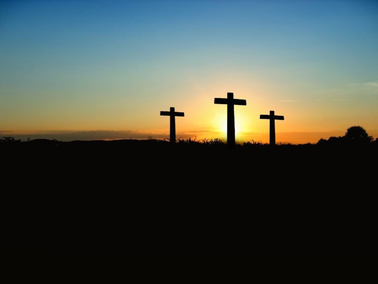 Silhouette of three crosses against a vibrant sunset sky.